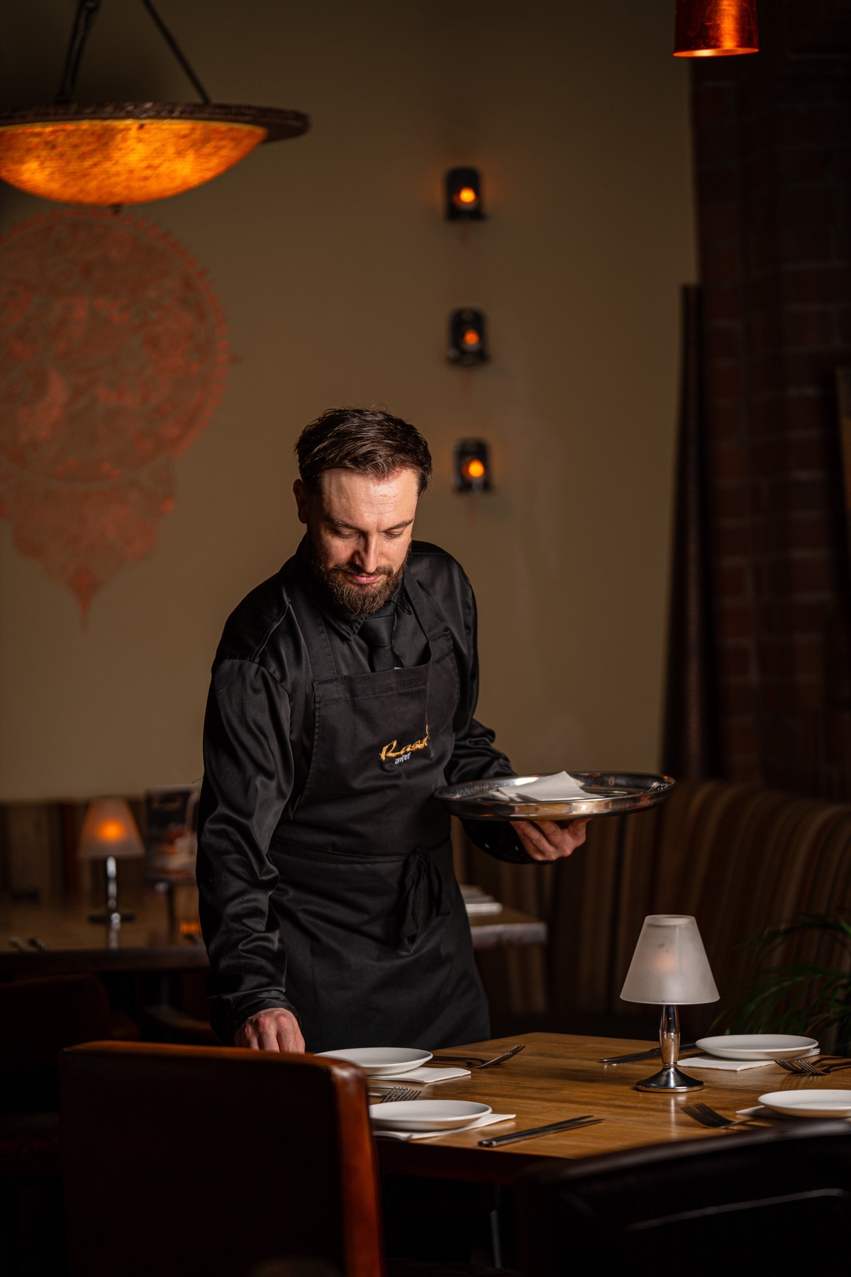 Front-of-house setting a table at Rasoi Waterfront
